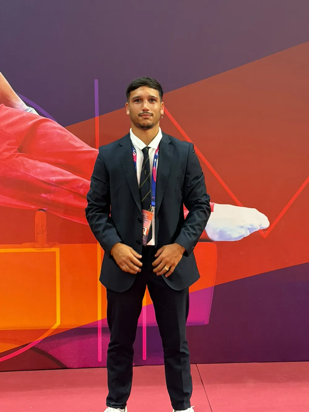 Alejandro con traje y acreditación de juez en una competición de gimnasia